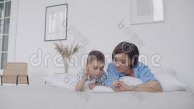 母亲和儿子在家里的卧室里使用数字平板电脑。 用数字显示快乐白人母子的正面观点